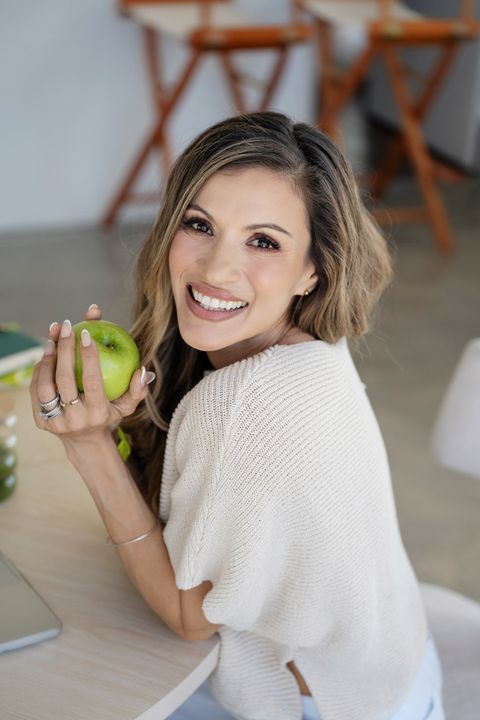 Cici McGuane smiling while holding a green apple