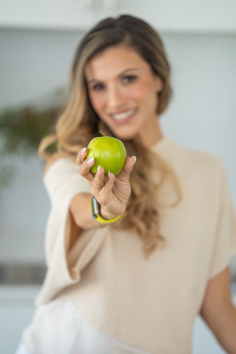 Cici holding a green apple toward the camera